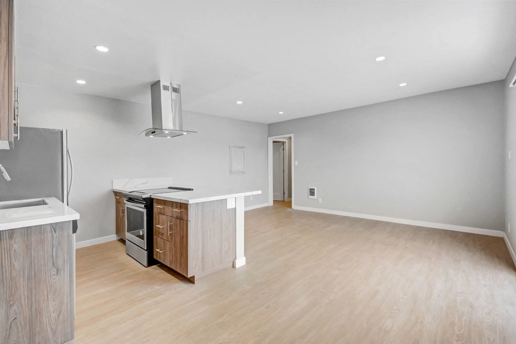 a renovated living room and kitchen with white walls and wood floors