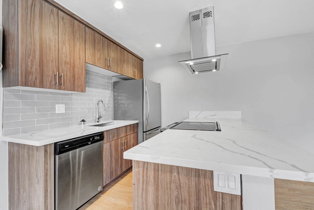 a kitchen with marble counter tops and wooden cabinets and a stainless steel refrigerator