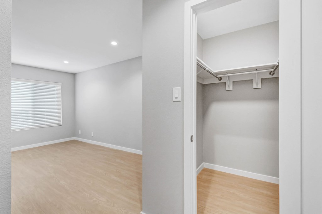 an empty room with a wood floor and grey walls and a white closet