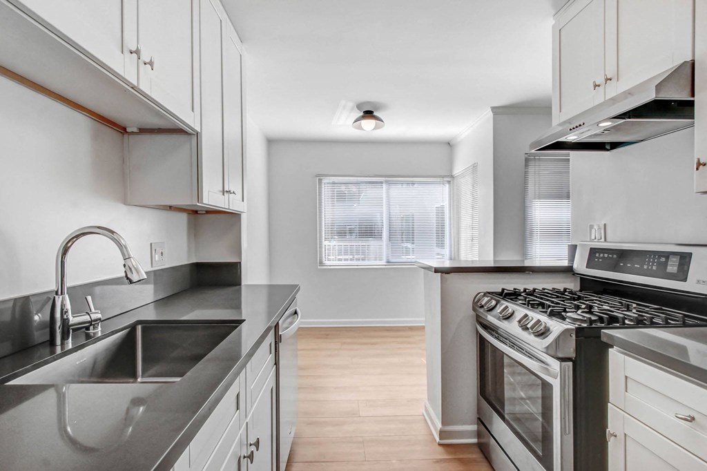 an empty kitchen with stainless steel appliances and white cabinets