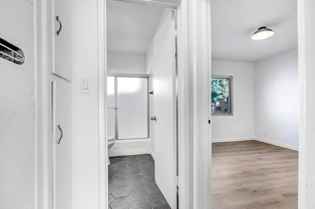 a renovated living room with white walls and a door to a bedroom