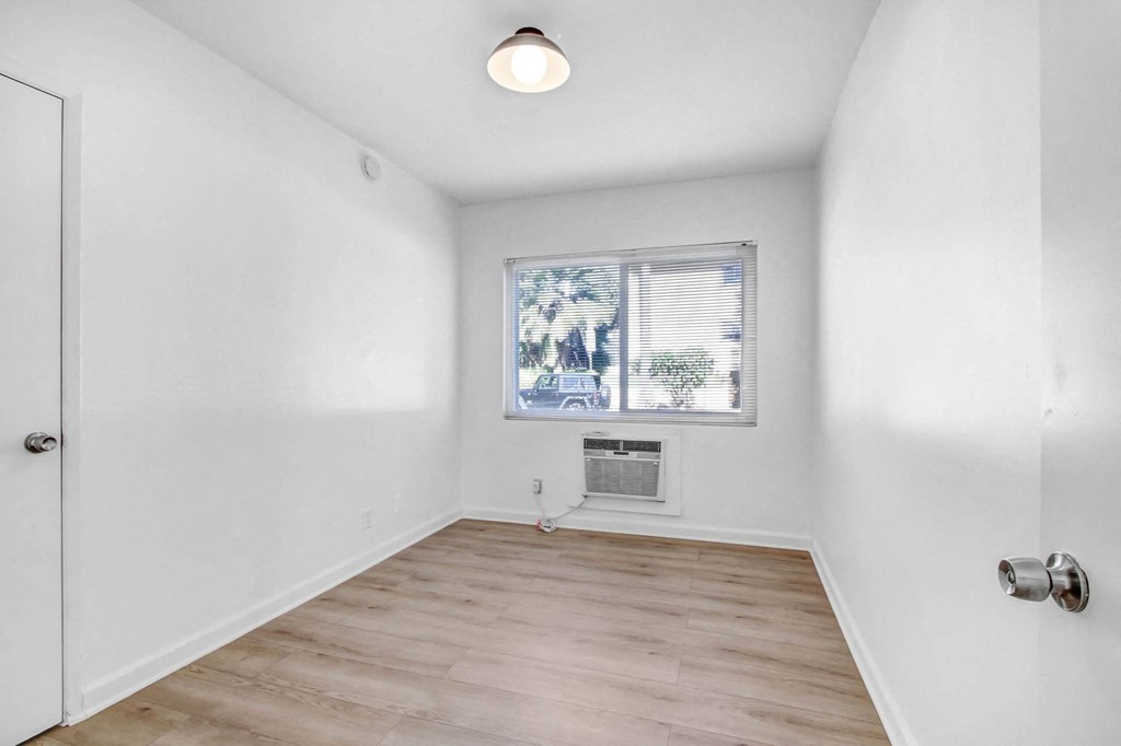 an empty living room with white walls and a window