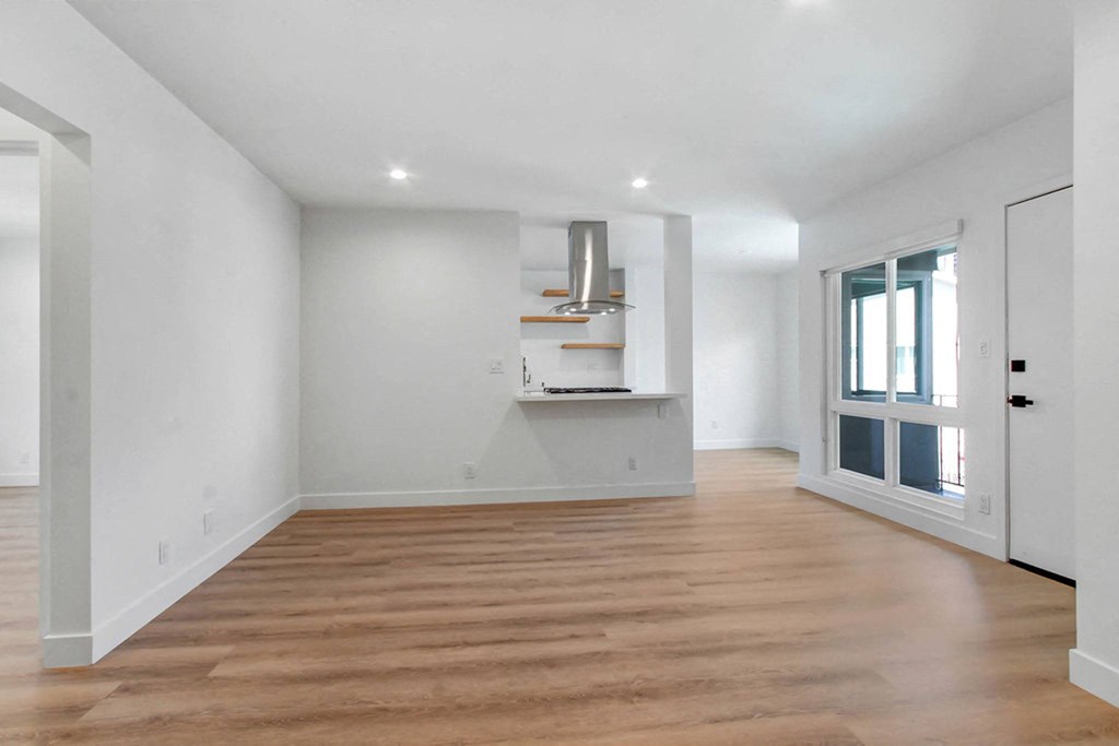 a living room with white walls and a door to a kitchen