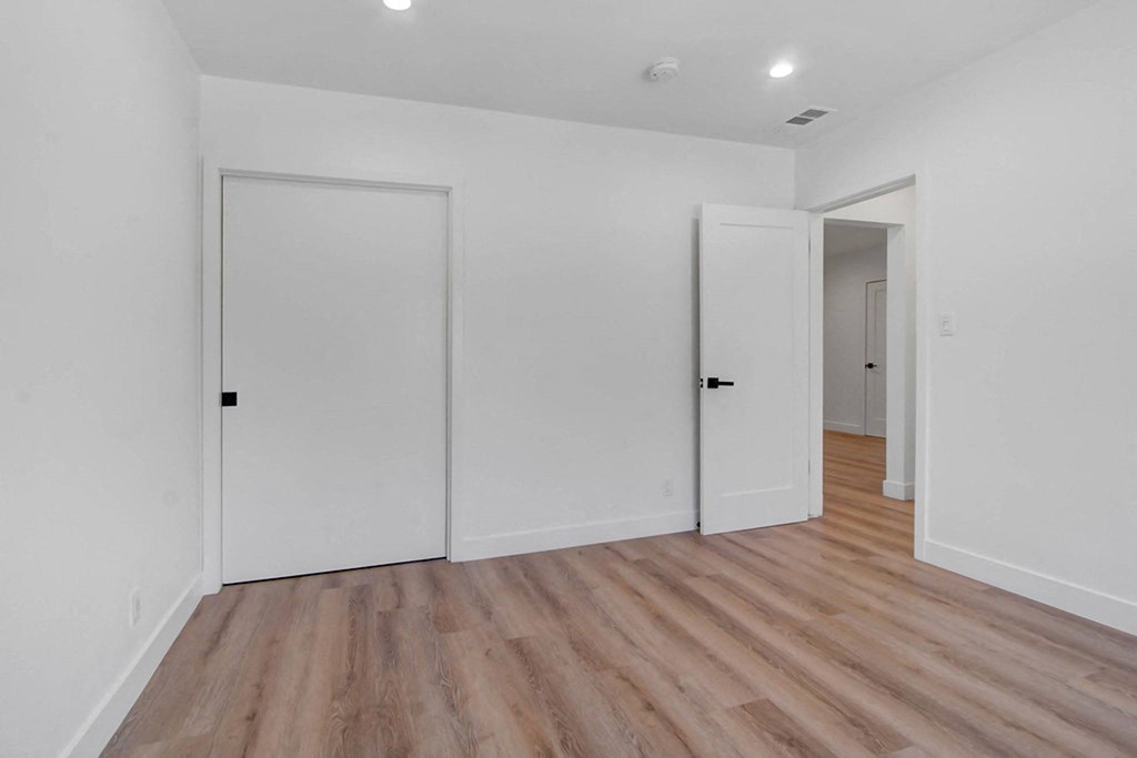a bedroom with white walls and wood floors