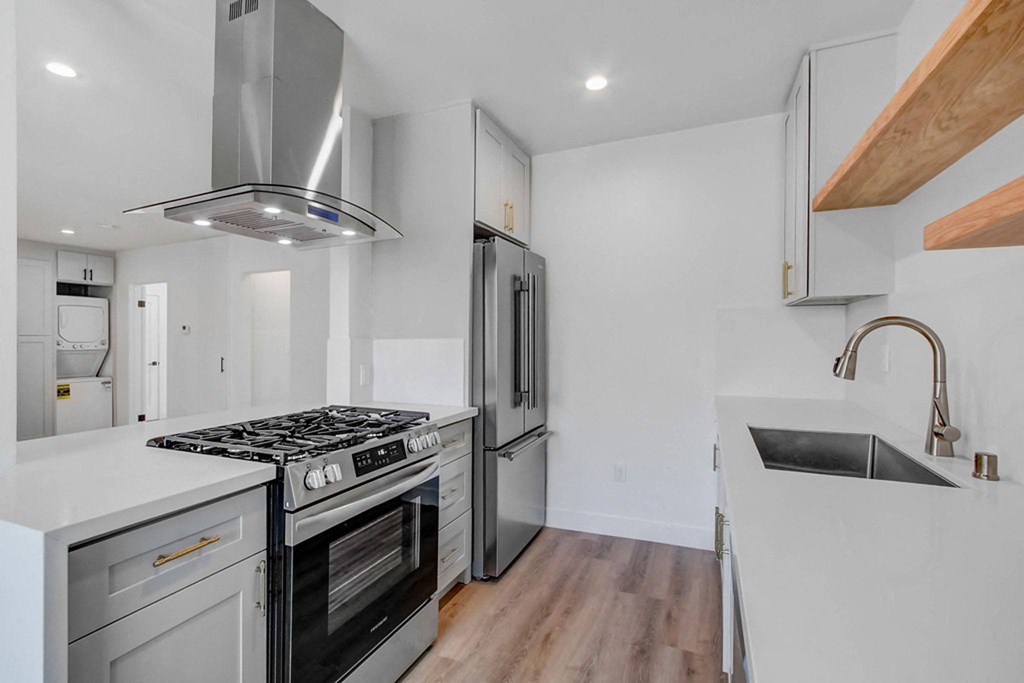 a white kitchen with stainless steel appliances and white counter tops