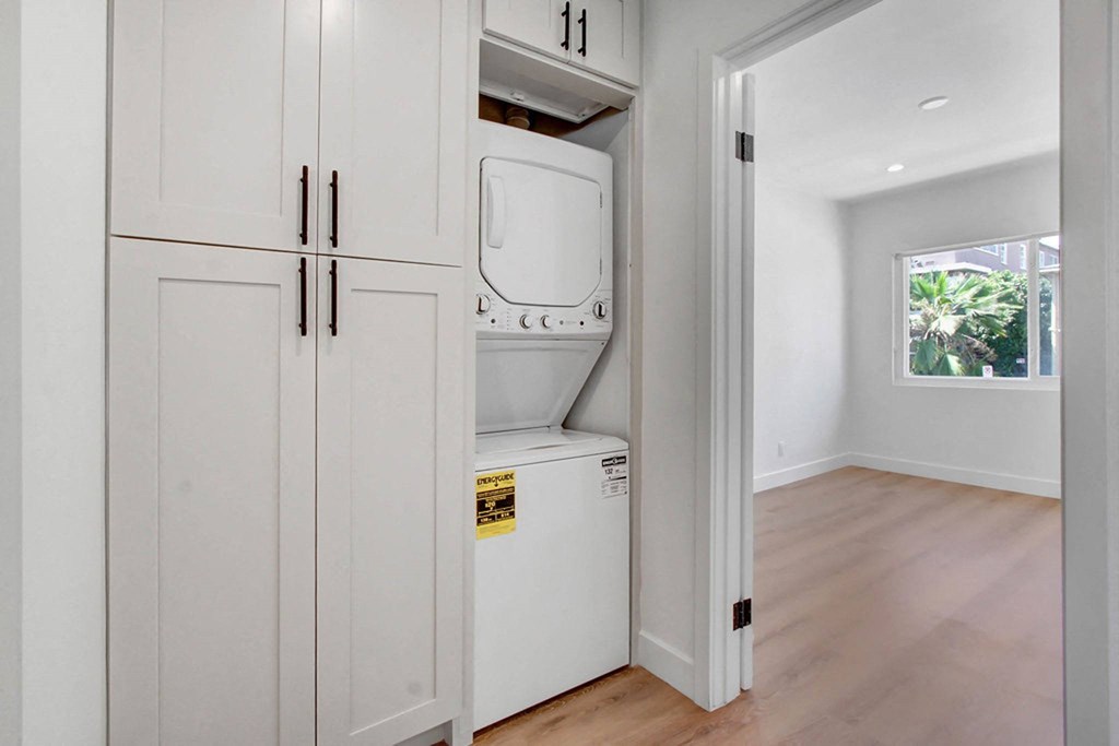 a laundry room with white cabinets and a washing machine in it
