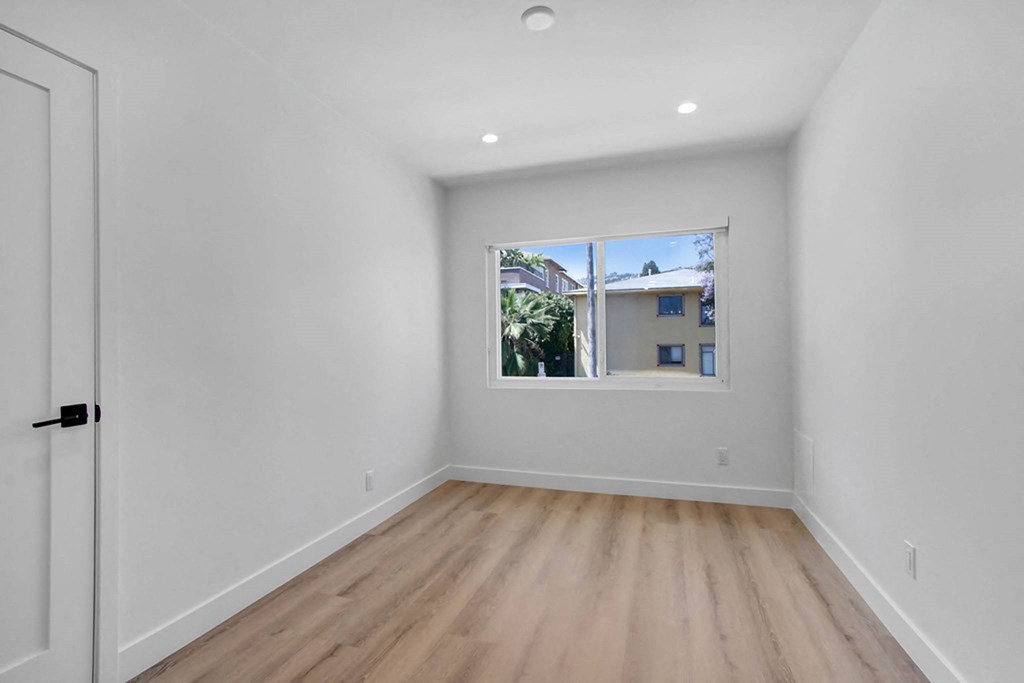 a bedroom with a window and hardwood floors