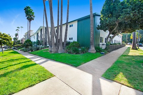 A green building with a white fence and a green lawn in front.