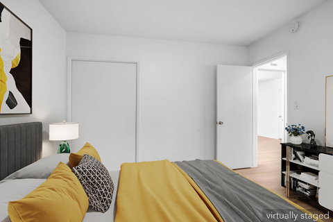 A bedroom with a bed covered in yellow and grey bedding.
