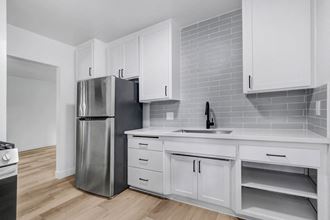 a kitchen with white cabinets and a stainless steel refrigerator