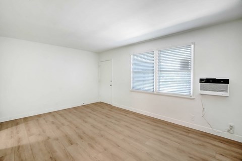 A room with wooden flooring and a window with blinds.