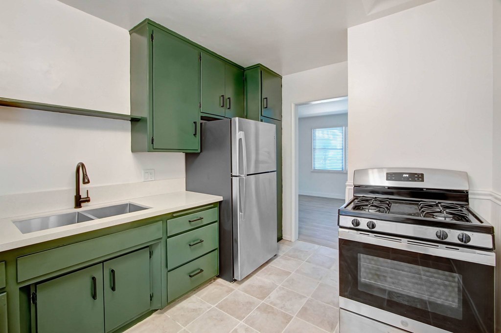 A kitchen with green cabinets and a stove.