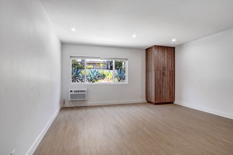 an empty living room with a window and wooden floors
