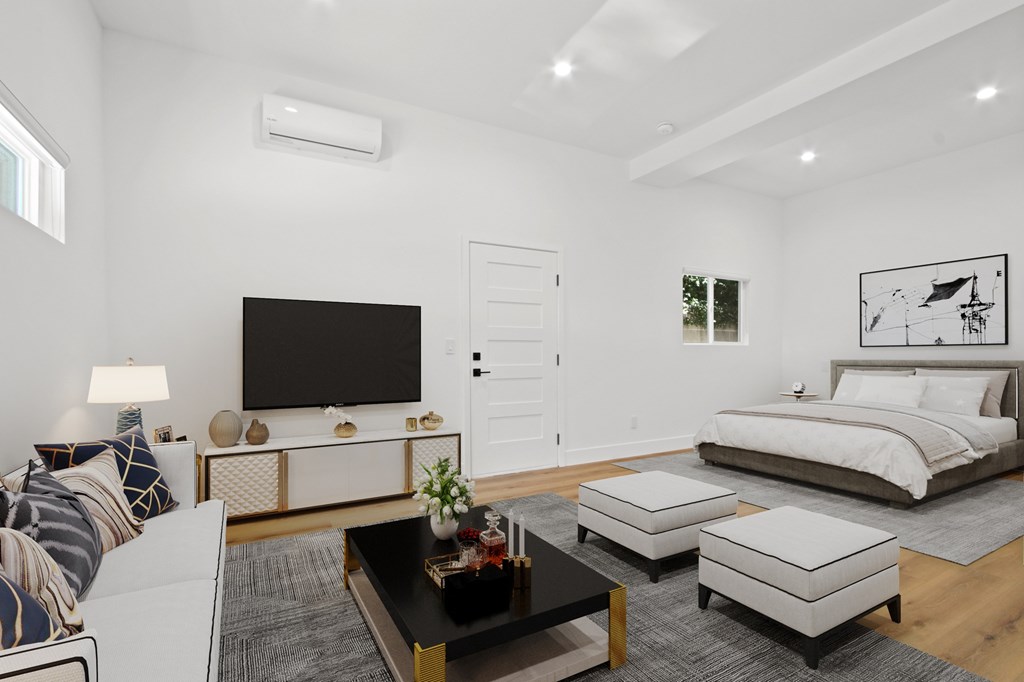 A modern living room with a flat screen TV, a sofa, a coffee table, and a bed.