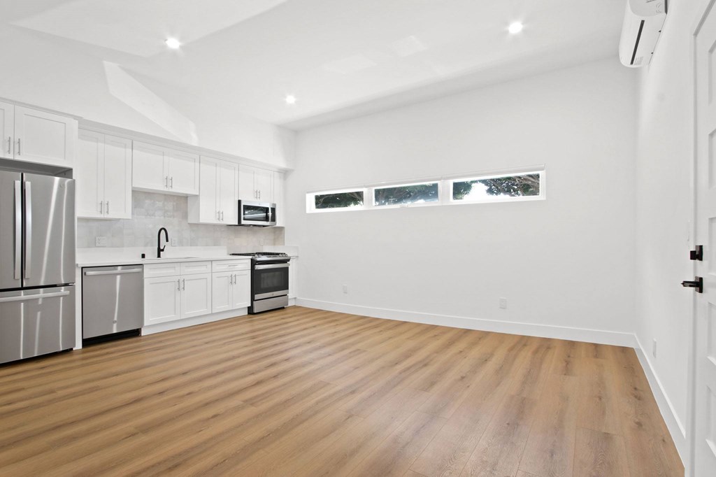 A spacious kitchen with wooden floors and white cabinets.