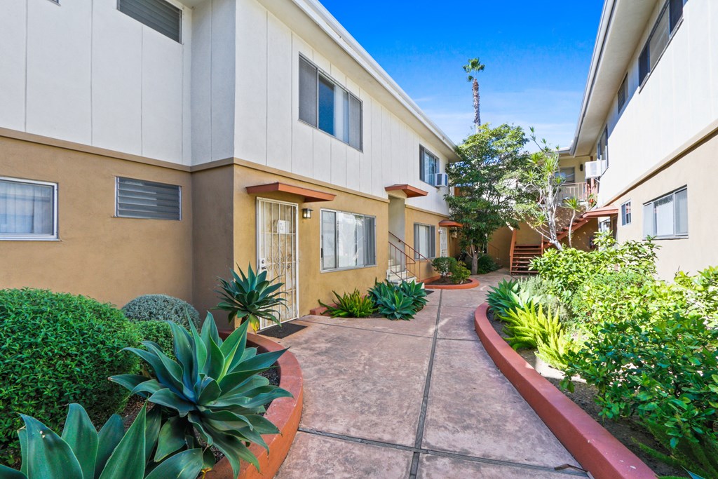 A sunny day at a residential complex with a pathway and green plants.