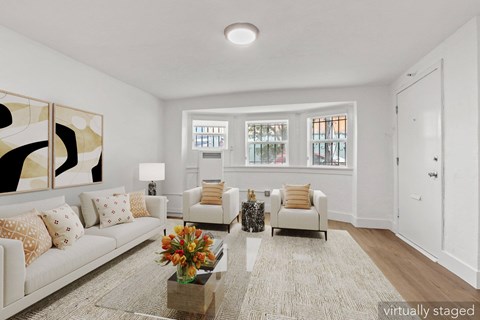 A living room with a white couch and a coffee table with a vase of flowers on it.