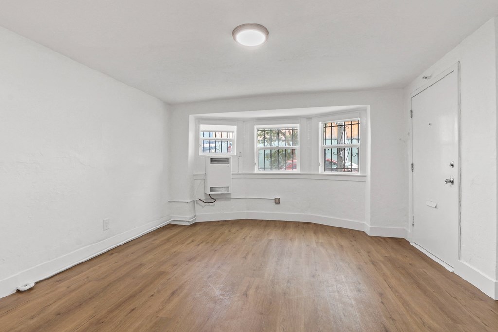 an empty living room with white walls and wood floors