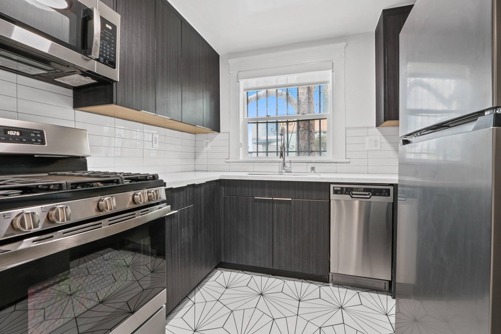 a kitchen with black and white tiles and stainless steel appliances