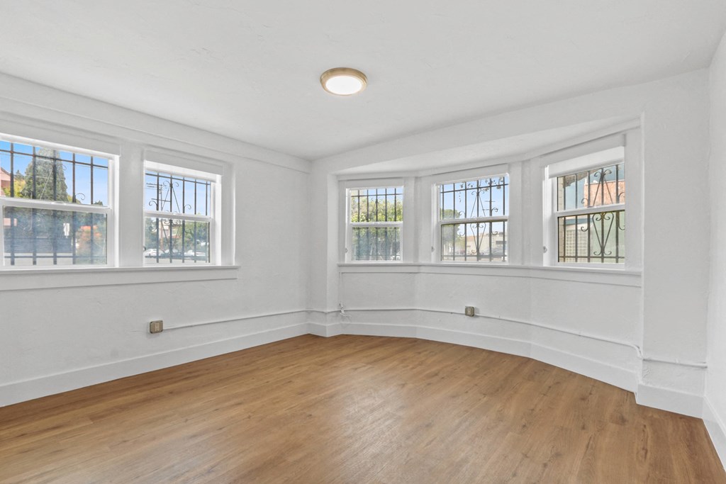 a living room with white walls and wood floors and windows