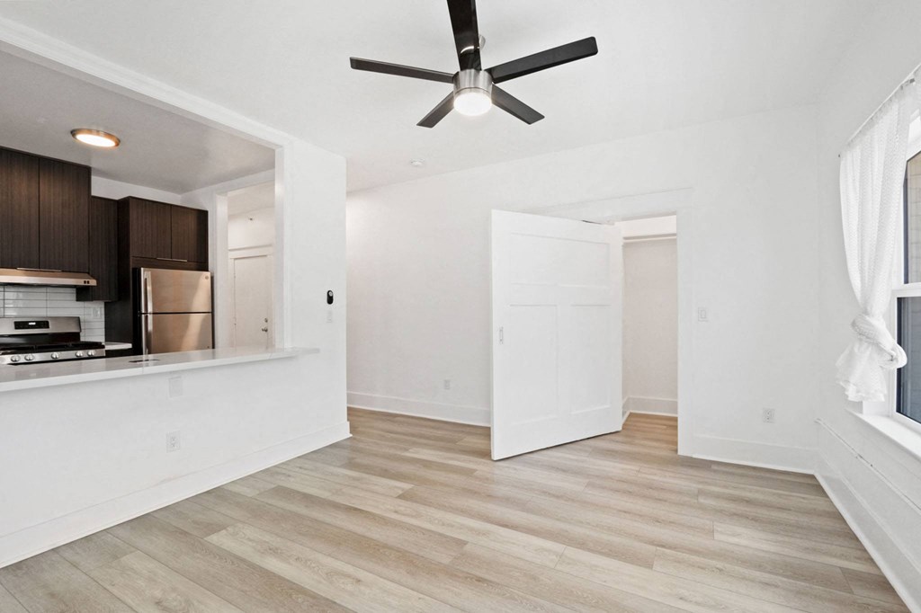 an empty living room and kitchen with a ceiling fan
