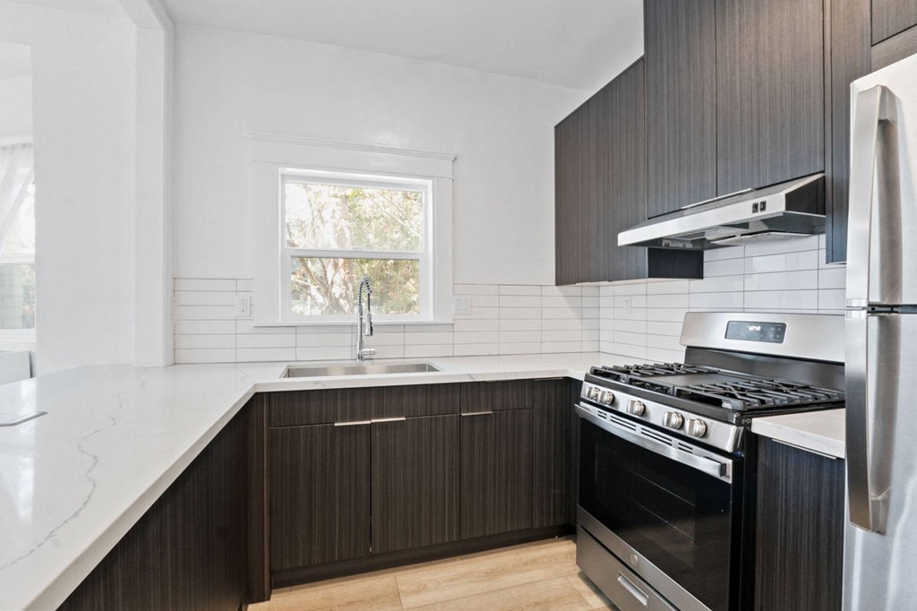 a kitchen with black and white cabinets and stainless steel appliances