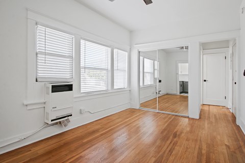 A room with wooden floors and a window with blinds.