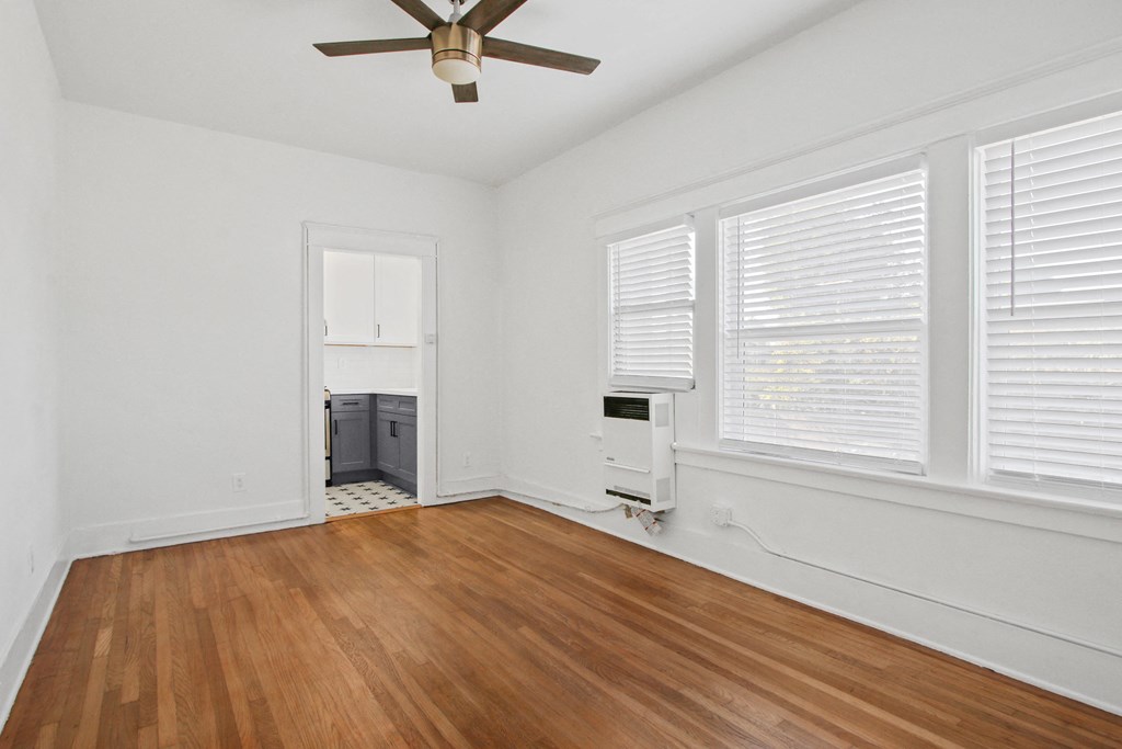 an empty living room with wood floors and a ceiling fan