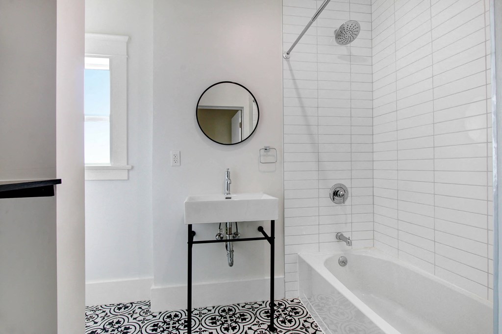 a white bathroom with black and white tile and a sink and tub