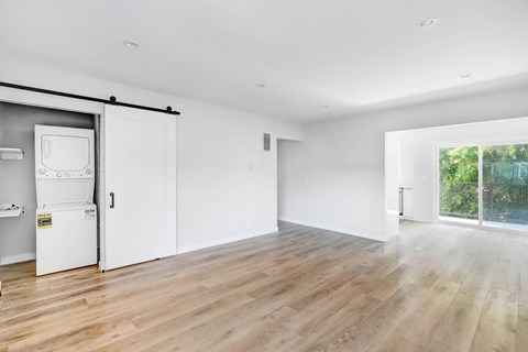 A white room with a wooden floor and a white fridge.