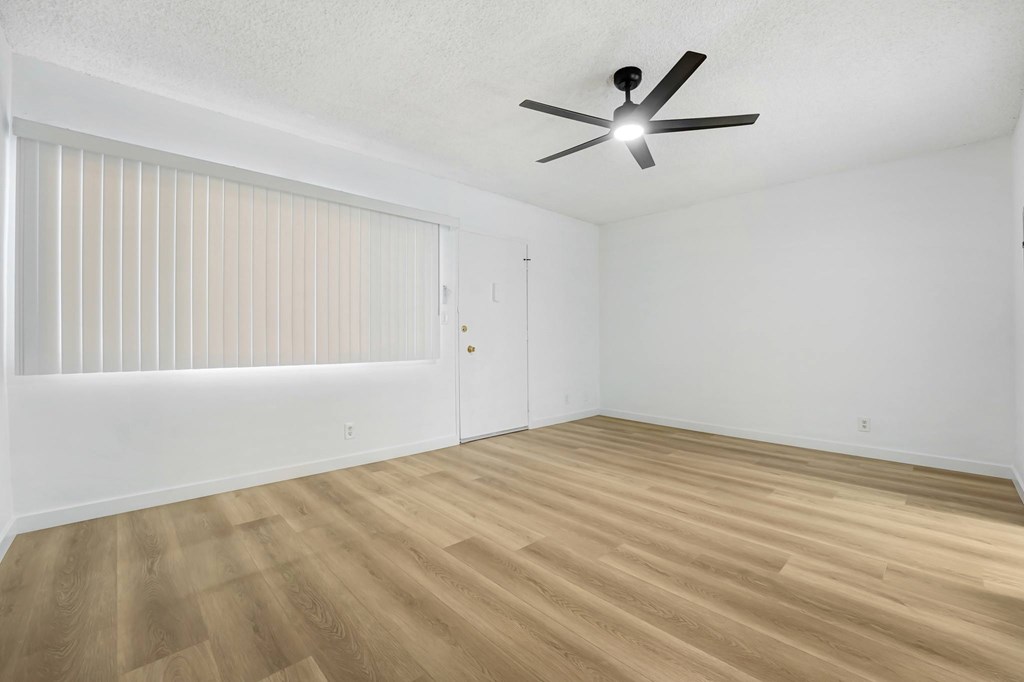 A room with a ceiling fan and wooden flooring.