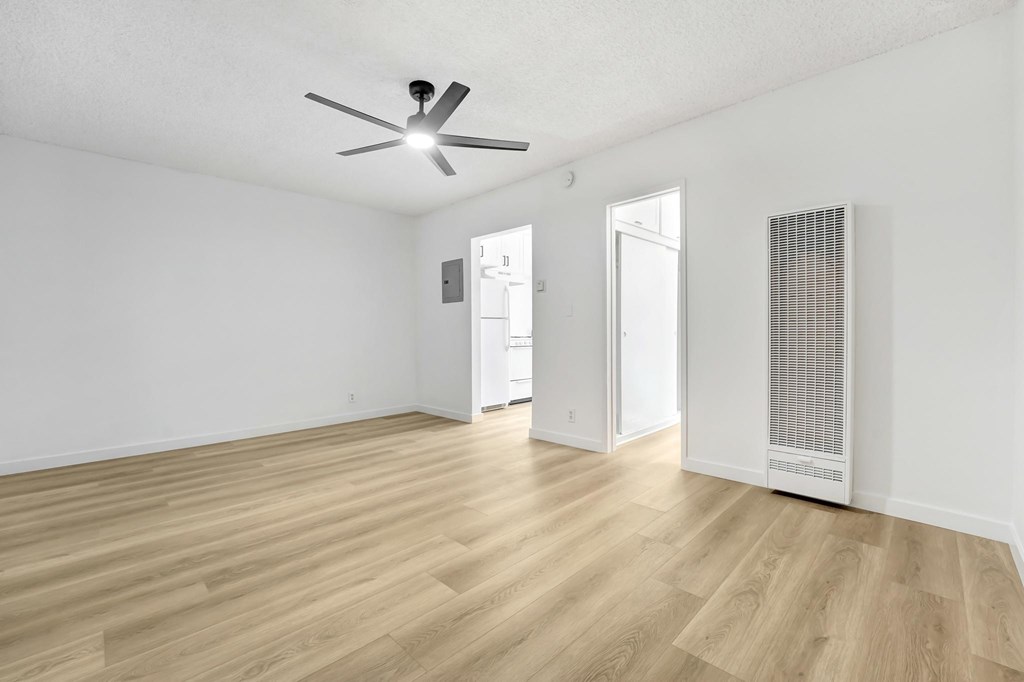 A room with a ceiling fan and wooden flooring.