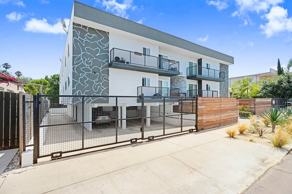 A modern two-story house with a white and grey exterior and a black metal fence.
