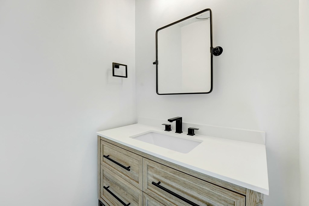 A bathroom with a white sink and a mirror above it.