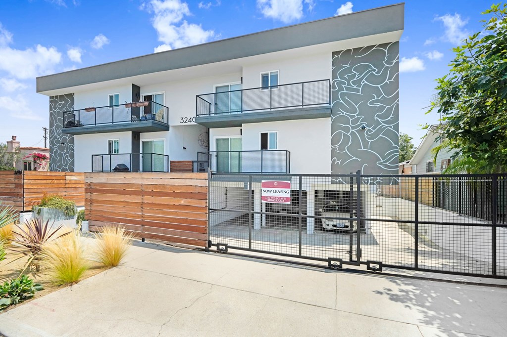 A modern two-story house with a balcony and a fence.