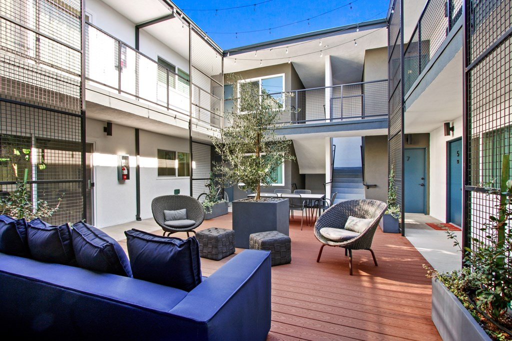A blue couch is on a wooden deck in front of a building.