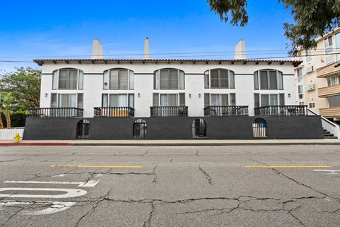 A white building with black railings and a fire hydrant in front.