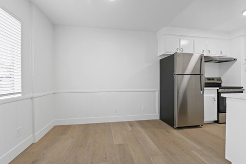 A kitchen with a stainless steel refrigerator and wooden flooring.