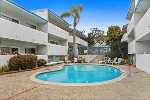 A swimming pool in a courtyard surrounded by white buildings.
