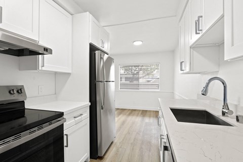an all white kitchen with white cabinets and black appliances