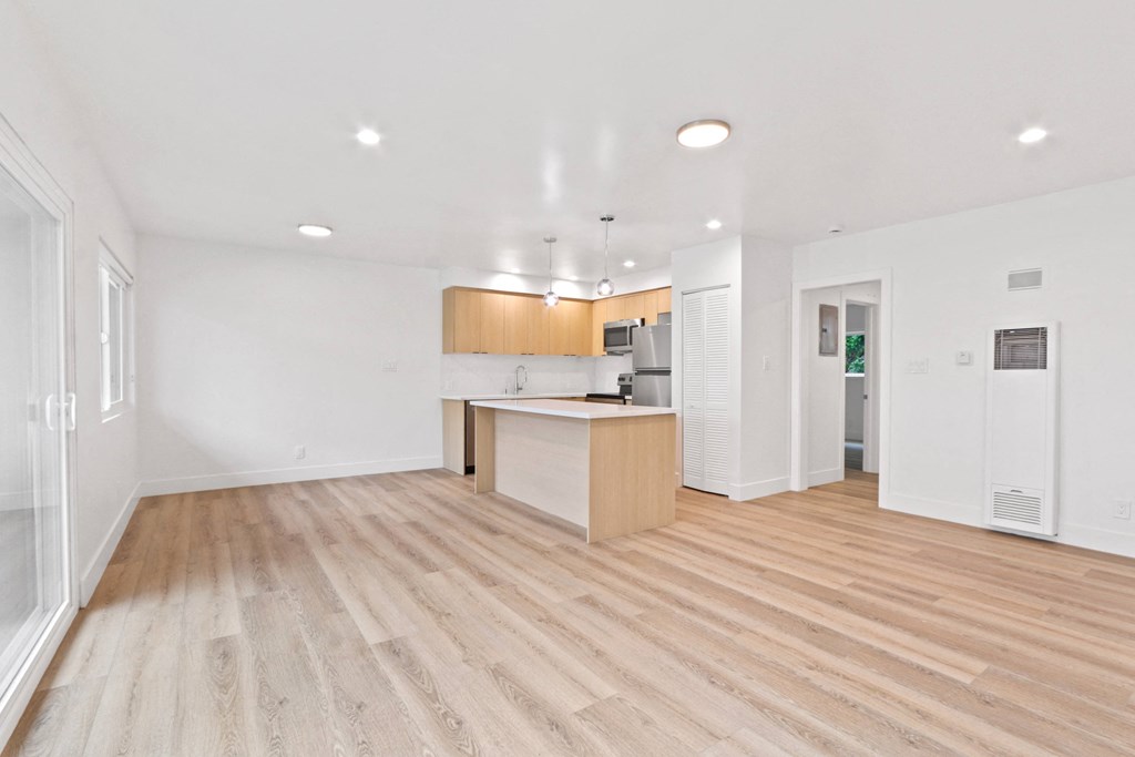 an empty living room and kitchen with wood flooring