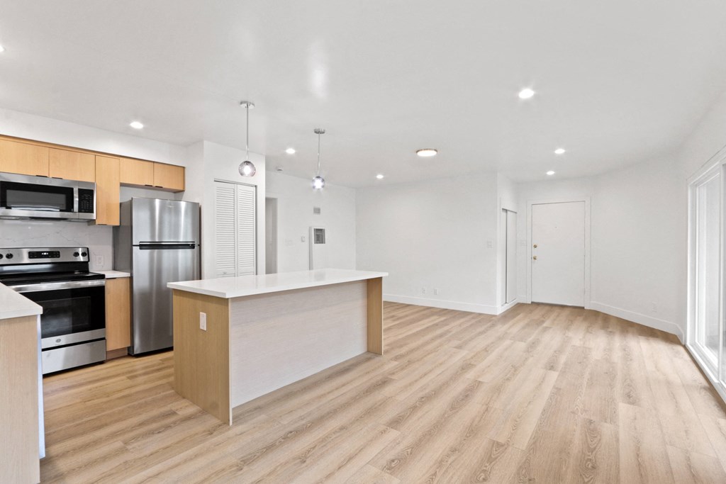 an open kitchen and living room with wood flooring and