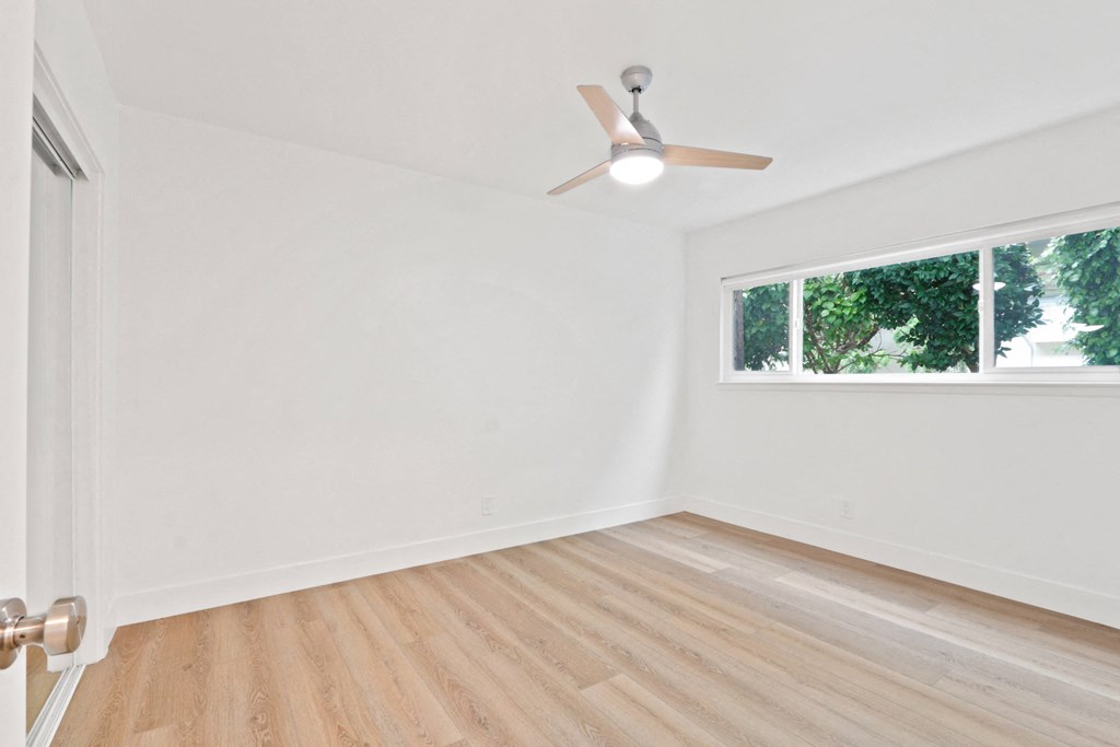 an empty room with a ceiling fan and a window