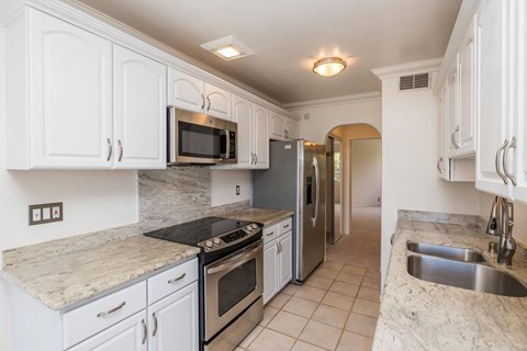 A kitchen with white cabinets and granite countertops.