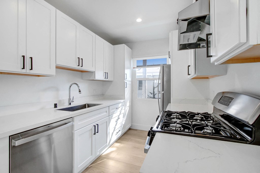 a white kitchen with white cabinets and stainless steel appliances