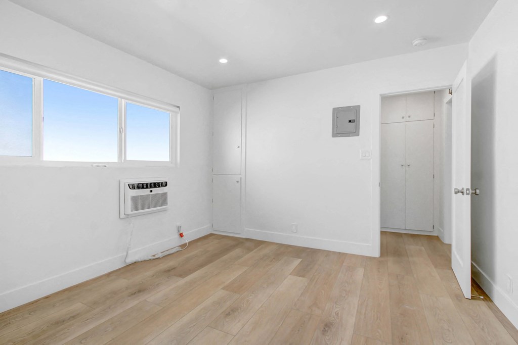 a living room with white walls and wooden floors and a window