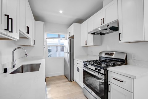 A kitchen with white cabinets and a stainless steel stove top oven.