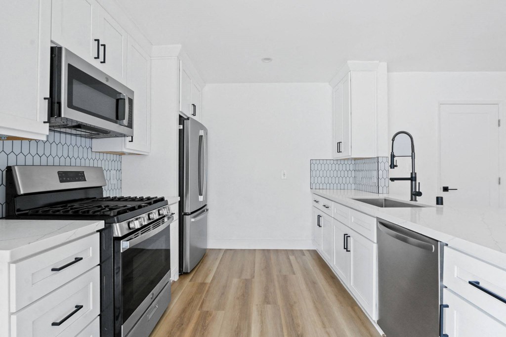 a renovated kitchen with white cabinets and stainless steel appliances