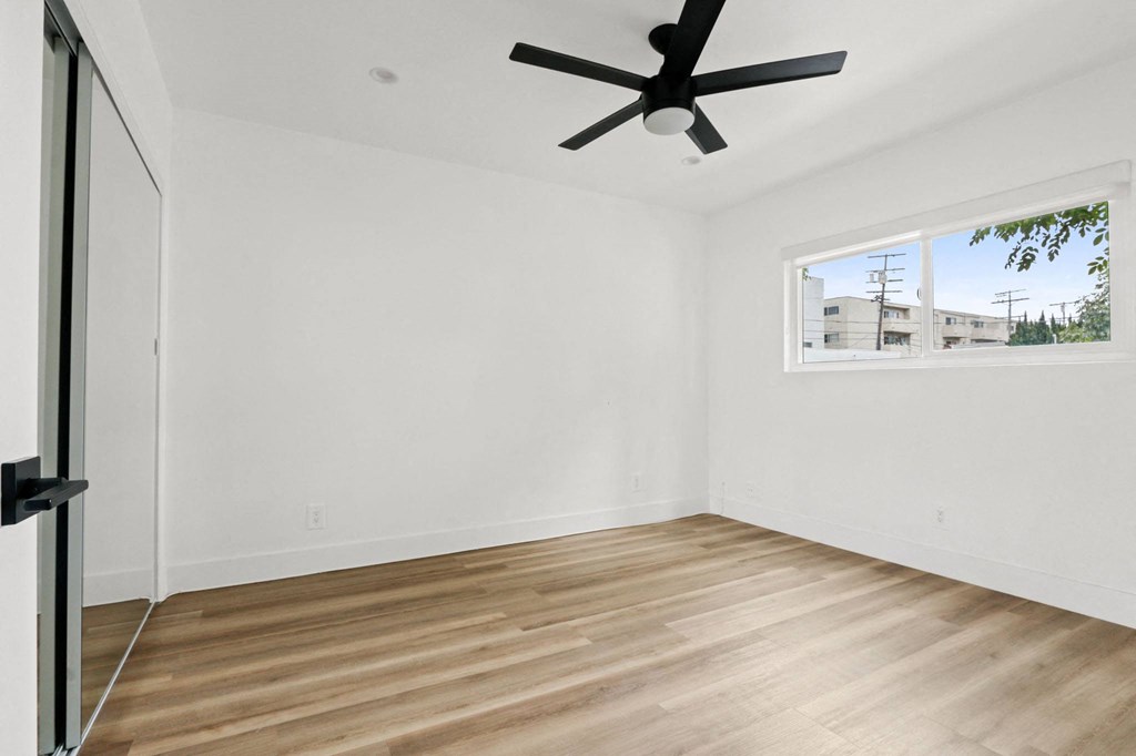 an empty room with a ceiling fan and a window