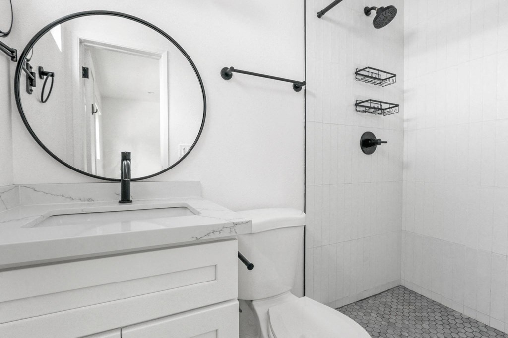 a white bathroom with a mirror and a white toilet and a shower
